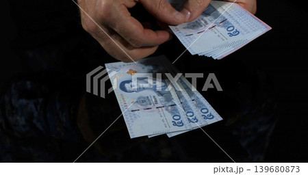 Counting money in a dimly lit setting with hands holding various bills Counting money in a dimly lit setting with hands holding various bills 139680873