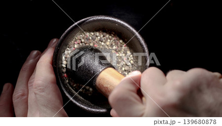 Grinding spices with a pestle in a mortar at a kitchen counter during daytime 139680878