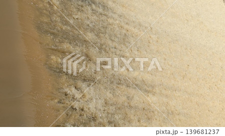 Abstract of fast-flowing, yellowish-brown water foaming and frothing as it rushes over an unseen edge creating a dynamic textured surface perfect for backgrounds and representing energy or pollution Abstract of fast-flowing, yellowish-brown water foaming and frothing as it rushes over an unseen edge creating a dynamic textured surface perfect for backgrounds and representing energy or pollution 139681237