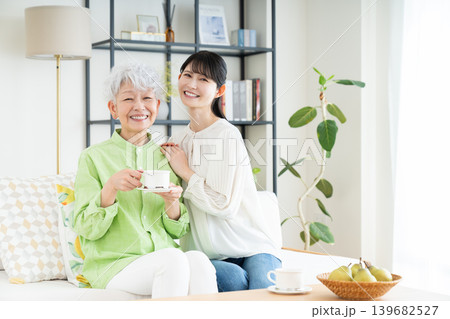 リビングでコーヒーを飲むシニアの母親とミドルの娘 139682527