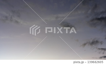 A beautiful sky with a soft gradient from a cool, dusky gray to a hint of pink and yellow at the bottom. A few small, scattered clouds add a touch of texture. 139682605