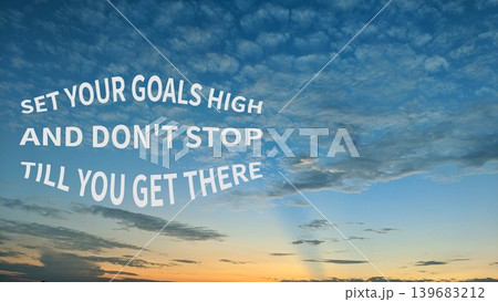 An empowering quote SET YOUR GOALS HIGH AND DON'T STOP TILL YOU GET THERE displayed against a beautiful blue and orange sunset sky with scattered clouds. 139683212