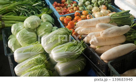 Market stall counter packed with colorful assorted vegetables including cabbage, tomatoes, daikon, chili, lime, Thai basil, cucumbers, eggplants, beans and Chinese cabbage. Fresh market concept Market stall counter packed with colorful assorted vegetables including cabbage, tomatoes, daikon, chili, lime, Thai basil, cucumbers, eggplants, beans and Chinese cabbage. Fresh market concept 139683940
