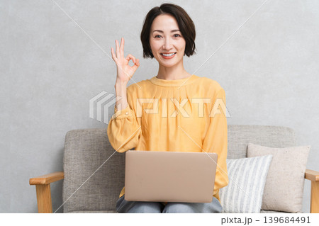 ソファーに座ってノートパソコンを使う女性 ライフスタイルイメージ ソファーに座ってノートパソコンを使う女性 ライフスタイルイメージ 139684491