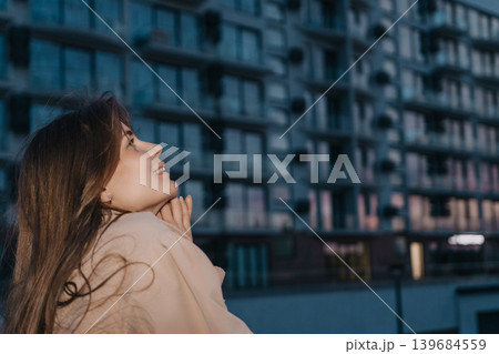 Woman urban dreaming smiling at city lights near modern apartment building during evening blue hour 139684559