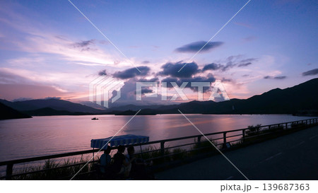 Serene twilight over a calm lake with distant mountains and a boat in Hong Kong Serene twilight over a calm lake with distant mountains and a boat in Hong Kong 139687363