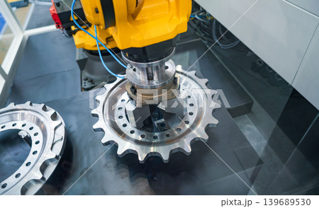 Industrial robotic arm holding metal gear component in automated factory cell. 139689530