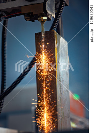 Wire EDM cutting of metal workpiece with sparks in industrial machine. Wire EDM cutting of metal workpiece with sparks in industrial machine. 139689545