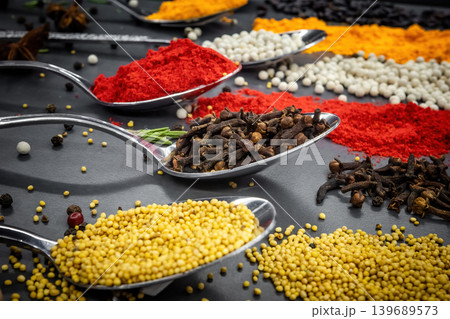 Collection of spices are spread out on a table. The spices include cumin, paprika, and turmeric Collection of spices are spread out on a table. The spices include cumin, paprika, and turmeric 139689573