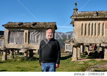 Mature man posing in front of the historic granaries of Lindoso in northern Portugal Mature man posing in front of the historic granaries of Lindoso in northern Portugal 139692120