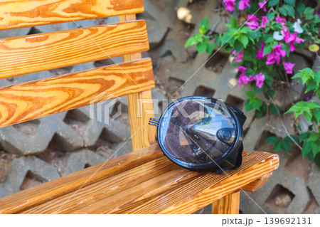 Abandoned snorkeling mask hanging on a bench, a forgotten treasure left behind by its owner, capturing the essence of summer adventures and ocean exploration 139692131