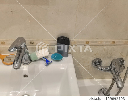 Bathroom sink area with razor and skincare products 139692308