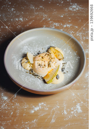 Close-up of elegant dish with egg, pear, and herbs on wooden surface 139692668