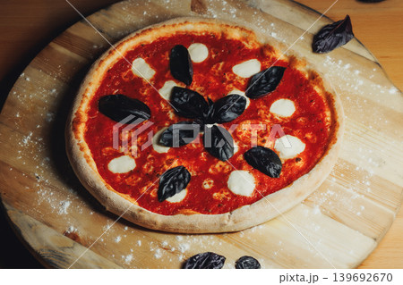Fresh pizza rests on wooden board 139692670