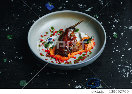 Duck breast elegantly plated with sauce and edible flowers on a dark background Duck breast elegantly plated with sauce and edible flowers on a dark background 139692709