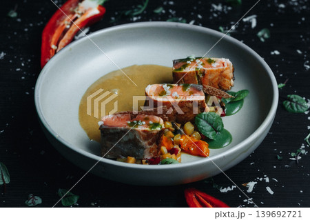 Succulent tuna with roasted veggies and flavorful sauce on dark plate Succulent tuna with roasted veggies and flavorful sauce on dark plate 139692721