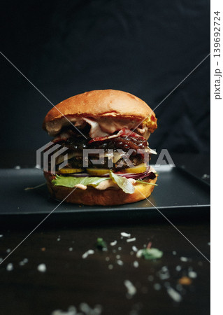 Delicious burger with bacon and lettuce on a black plate Delicious burger with bacon and lettuce on a black plate 139692724