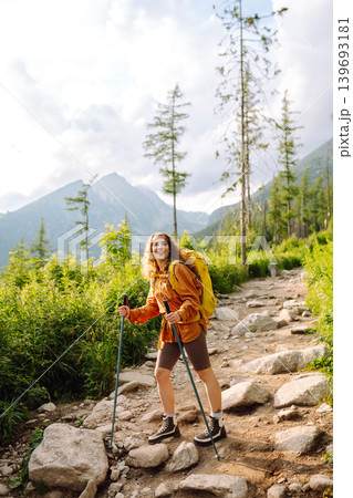 Young woman traveler hiking poles on trail among the mountains. Hiking. Active lifestyle. Young woman traveler hiking poles on trail among the mountains. Hiking. Active lifestyle. 139693181