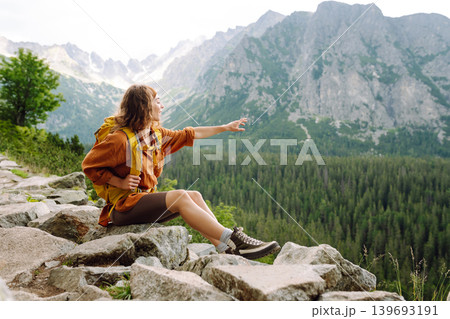 Young traveler woman with a yellow backpack on a cliff. Sports concept, traveler. Active lifestyle. Young traveler woman with a yellow backpack on a cliff. Sports concept, traveler. Active lifestyle. 139693191