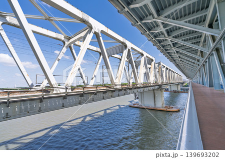 白い鋼鉄トラス鉄道橋・河川越え幾何学構造と青空の透視構図 白い鋼鉄トラス鉄道橋・河川越え幾何学構造と青空の透視構図 139693202