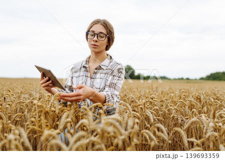 Woman agronomist in a field with a tablet checks the growth of the crop. New harvest concept. 139693359
