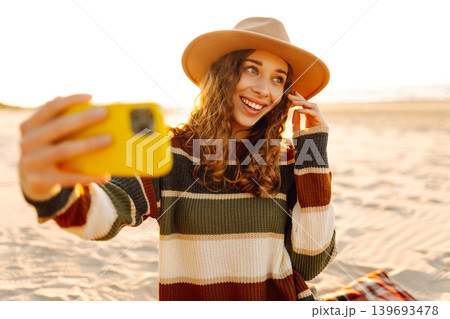 Smiling woman taking a selfie as she poses for camera on her mobile phone. Sunset. Blogging, travel Smiling woman taking a selfie as she poses for camera on her mobile phone. Sunset. Blogging, travel 139693478