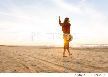 Beautiful woman on the beach in cold weather enjoying time in the sunset. Lifestyle, adventure. 139693493