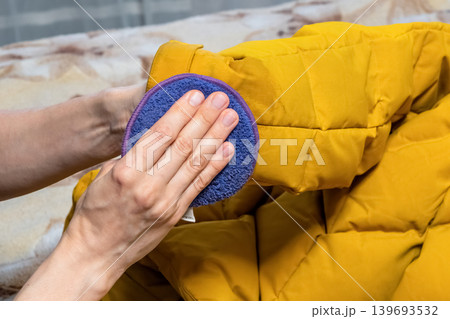 Hands gently wipe the yellow jacket with a microfiber pad. Hands gently wipe the yellow jacket with a microfiber pad. 139693532