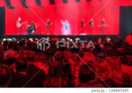Crowd watching live concert on stage with band under dramatic red lighting and blurred performers 139693565