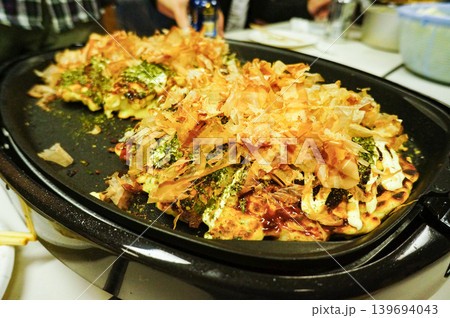 焼き上がったお好み焼きに鰹節をふりかける 焼き上がったお好み焼きに鰹節をふりかける 139694043
