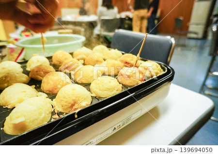 焼き上がった丸いたこ焼きを串で仕上げる光景 焼き上がった丸いたこ焼きを串で仕上げる光景 139694050
