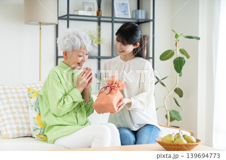 シニアの母親にプレゼントを渡すミドルの娘 139694773