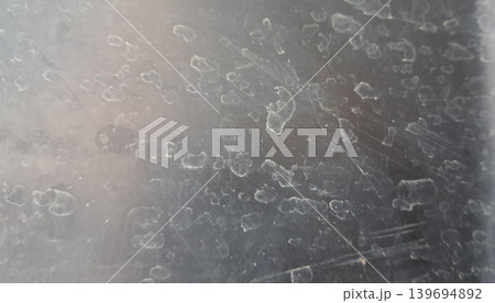 Close-Up Texture of Water Spots and Mineral Stains on Scratched Glass Surface 139694892