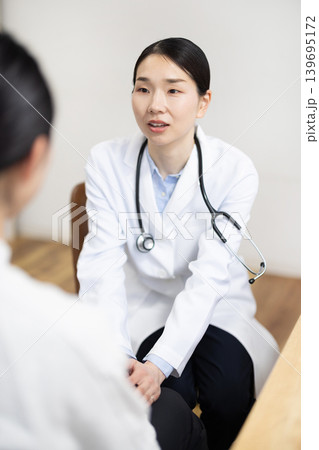 患者の手を握って笑顔で励ます白衣を着た日本人女性医師 患者の手を握って笑顔で励ます白衣を着た日本人女性医師 139695172