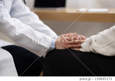 患者の手を握る白衣を着た女性医師の手元のクローズアップ 139695173