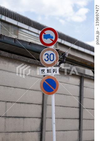 ブロック塀の前に並ぶ道路標識と速度制限30の標識 139697477