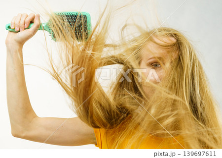 Blonde girl long tangled hair holds brush 139697611