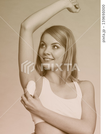 Girl applying stick deodorant in armpit. 139698000