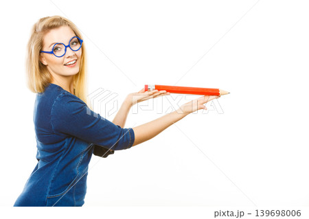 Positive woman holds big pencil in hand Positive woman holds big pencil in hand 139698006