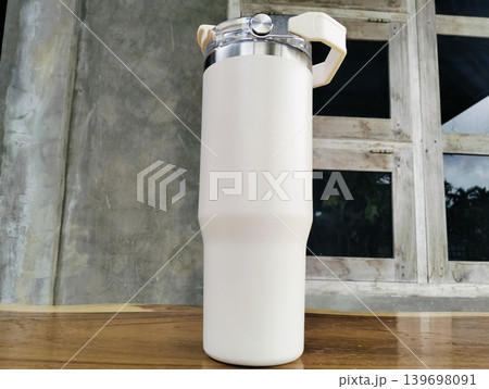 White Stainless Steel Tumbler with Silver Handle on Wooden Table 139698091