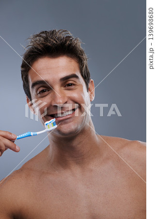 Portrait, toothbrush and man with a smile, clean and morning routine on grey studio background. Happy, person or model with dental hygiene or oral health with fresh breath or toothpaste with wellness Portrait, toothbrush and man with a smile, clean and morning routine on grey studio background. Happy, person or model with dental hygiene or oral health with fresh breath or toothpaste with wellness 139698680