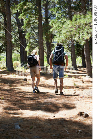 Couple of friends walking, trekking in nature and travel fitness, adventure or cardio in forest with wellness. Back of people hiking with backpack on path, eco friendly and carbon footprint journey 139698737