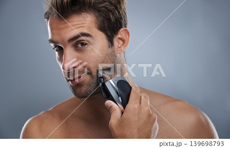 Man, beard and electric razor in studio portrait for grooming, skincare and wellness by grey background. Person, model and shaving with hygiene, facial hair removal and product for cosmetic change 139698793