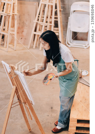 Female artist wears black hat posing near picture indoor the studio Female artist wears black hat posing near picture indoor the studio 139698846