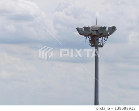 Stadium floodlight tower against cloudy sky with dramatic weather and minimal background Stadium floodlight tower against cloudy sky with dramatic weather and minimal background 139698915