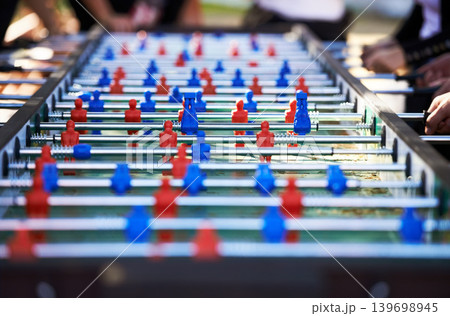 Foosball table, competitive and leisure with people playing a game outdoor at a music festival together. Party, event or social gathering with friends at a carnival for tabletop soccer or football Foosball table, competitive and leisure with people playing a game outdoor at a music festival together. Party, event or social gathering with friends at a carnival for tabletop soccer or football 139698945