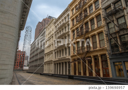 New york, usa august 18,2024. Cobblestone street in manhattan's tribeca district showcasing typical historic cast iron architecture with a modern skyscraper in background New york, usa august 18,2024. Cobblestone street in manhattan's tribeca district showcasing typical historic cast iron architecture with a modern skyscraper in background 139698957