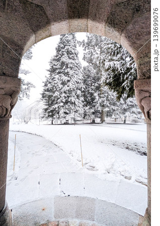 Snowy winter landscape framed by stone archway of a building. Snowy winter landscape framed by stone archway of a building. 139699076