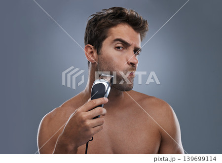Man, shaving and machine in studio for beard grooming, skincare and portrait by grey background. Person, model and self care for hygiene, facial hair removal and electric razor for cosmetic change Man, shaving and machine in studio for beard grooming, skincare and portrait by grey background. Person, model and self care for hygiene, facial hair removal and electric razor for cosmetic change 139699114