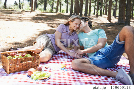 Happy couple, kiss and relax in nature for picnic, love or support in affection, date or outdoor bonding. Woman and man sitting on floor with basket of fruit for embrace, eating or romance in forest Happy couple, kiss and relax in nature for picnic, love or support in affection, date or outdoor bonding. Woman and man sitting on floor with basket of fruit for embrace, eating or romance in forest 139699118